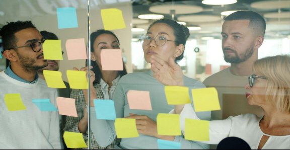 Professionals brainstorming on a transparent whiteboard